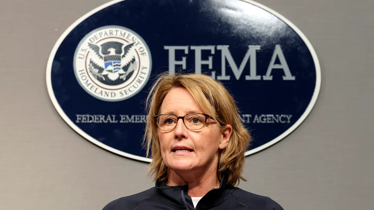 A person stands in front of a sign reading "FEMA"