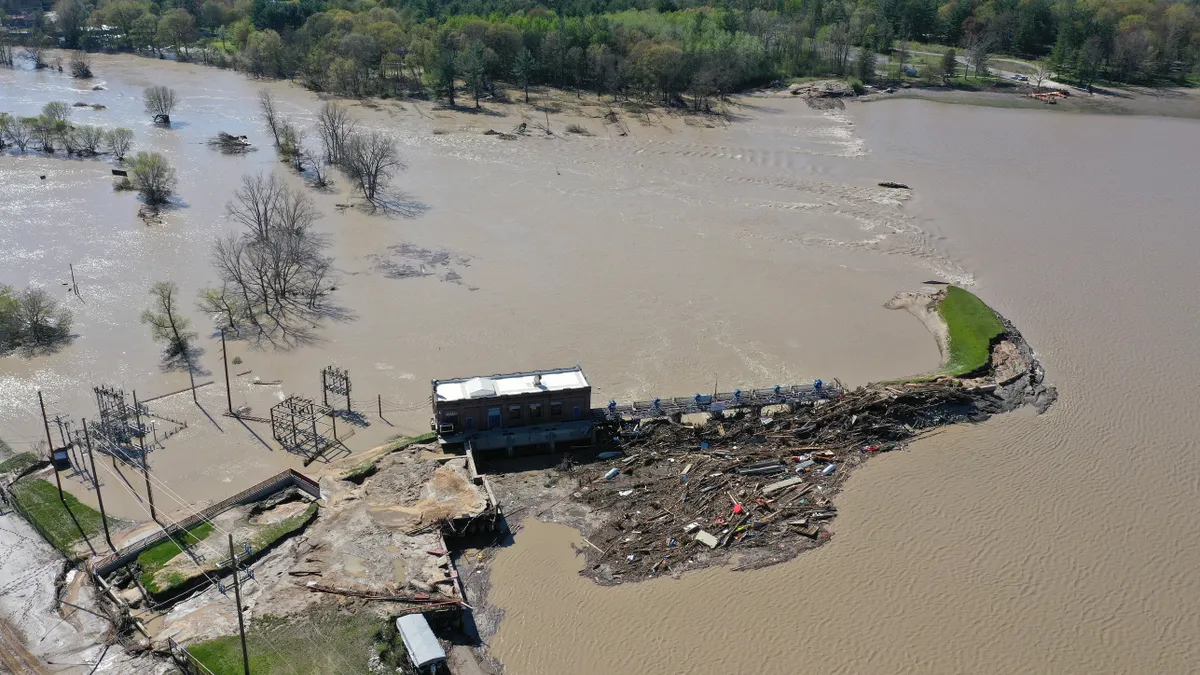 Aerial view of a broken dam structure, mostly overwhelmed by water.