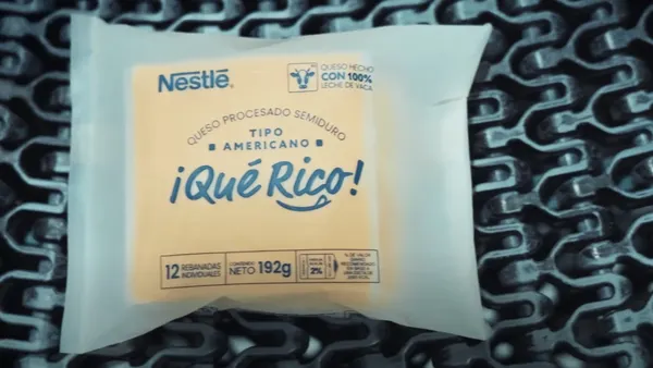 A square chunk of cheese in a wrapper with messaging for Nestlé's ¡Qué Rico! cheese brand.