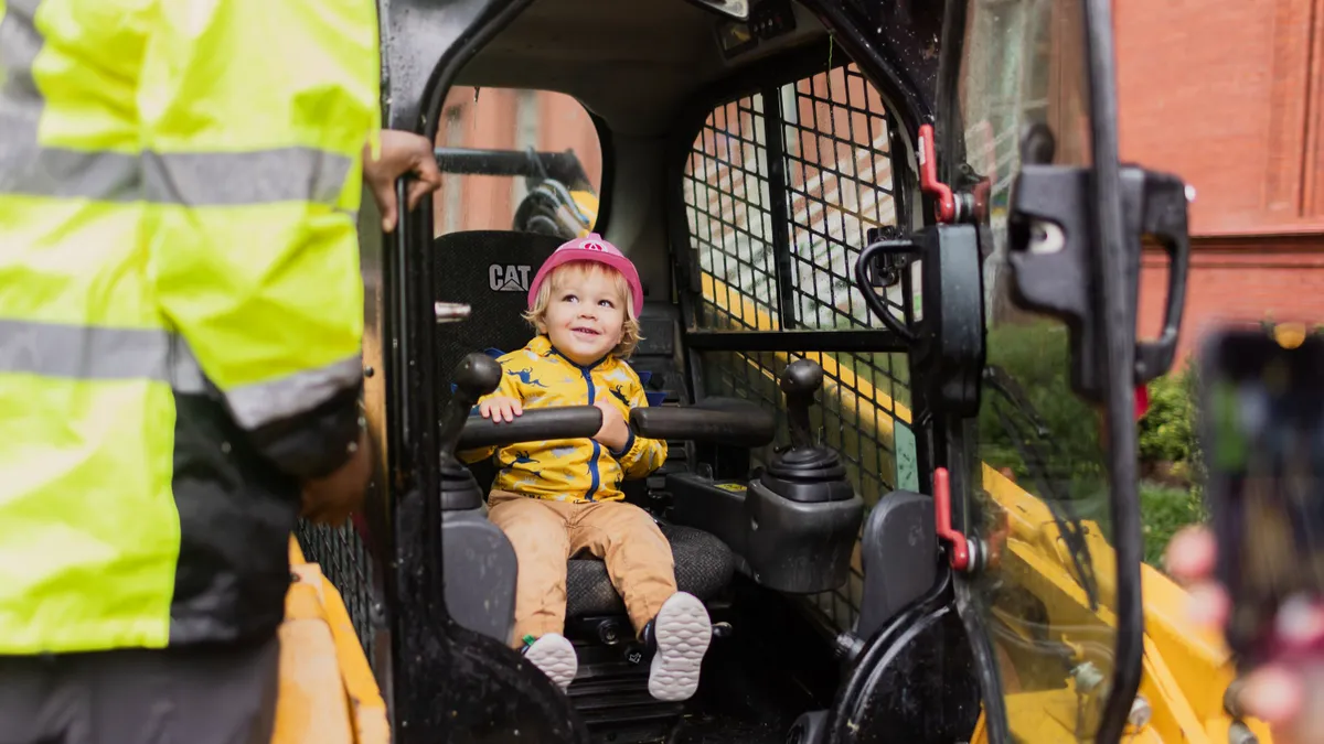 A child sits in a piece of large construction machinery.