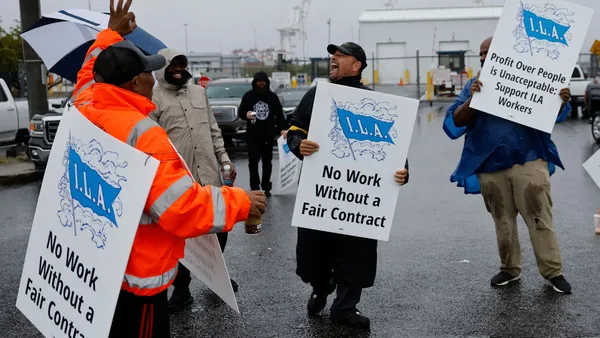 Dockworkers hold picket sign, striking at a port in Baltimore.