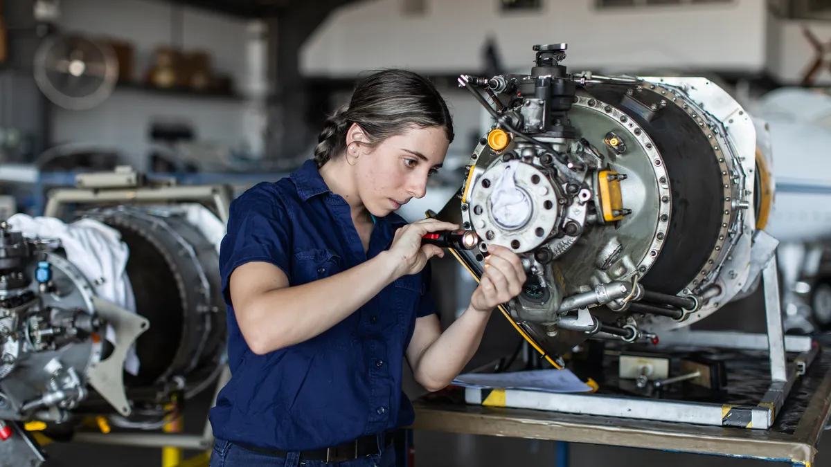 A aircraft engineer apprentice works on plane parts