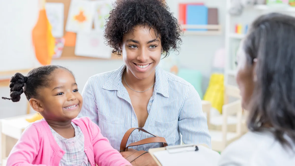 A mother has a conference with her young daughter's preschool teacher.