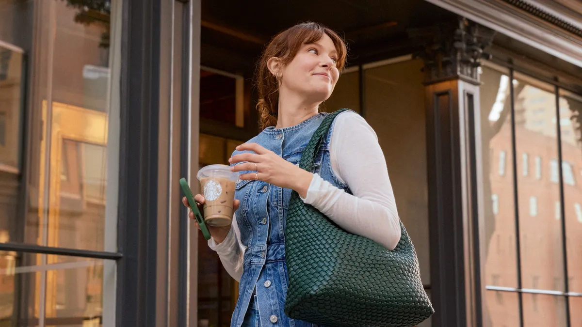 A smiling white woman with a Starbucks cup.