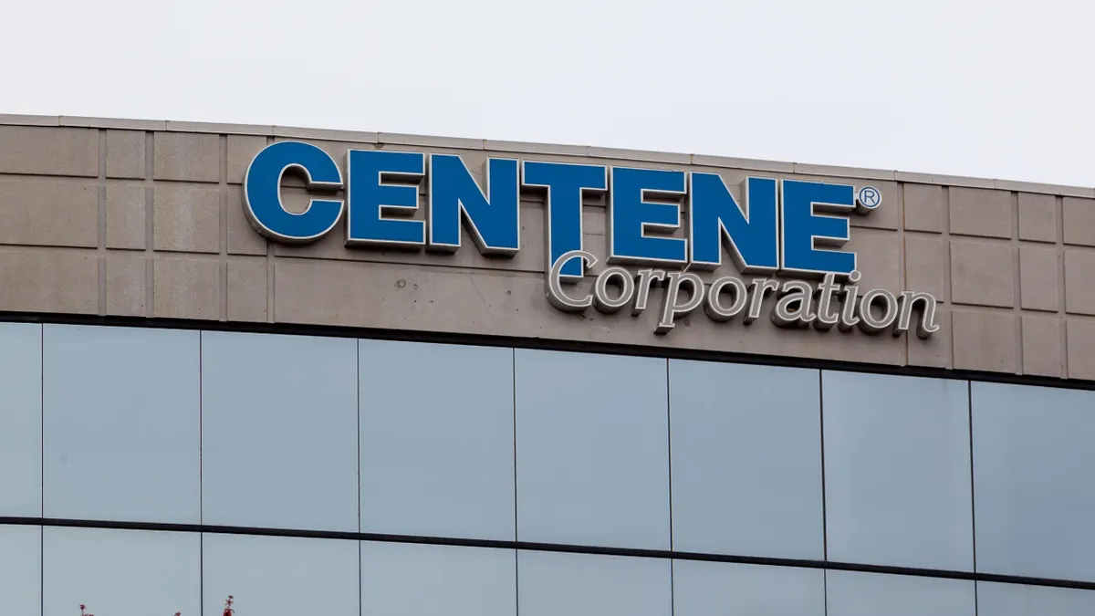 A modern office building facade with blue-tinted windows and a curved design. A sign near the roof reads “Centene Corporation” in blue and gray lettering.