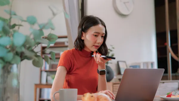A woman talks on her phone while using a computer.
