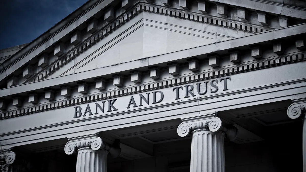 A classical building with columns is pictured with the words "bank and trust" inscribed above the columns.