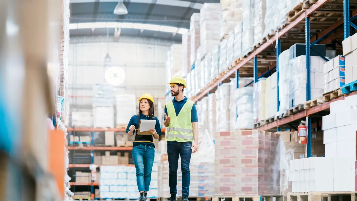 Two employees checking inventory on warehouse racks.