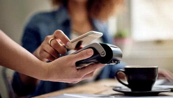 Closeup shot of a woman paying using NFC technology in a cafe