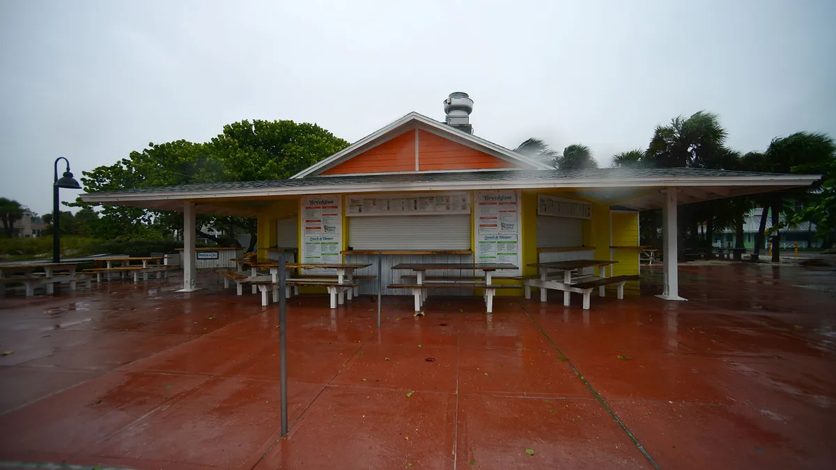 An image of a closed and boarded up restaurant during Hurricane Ian.