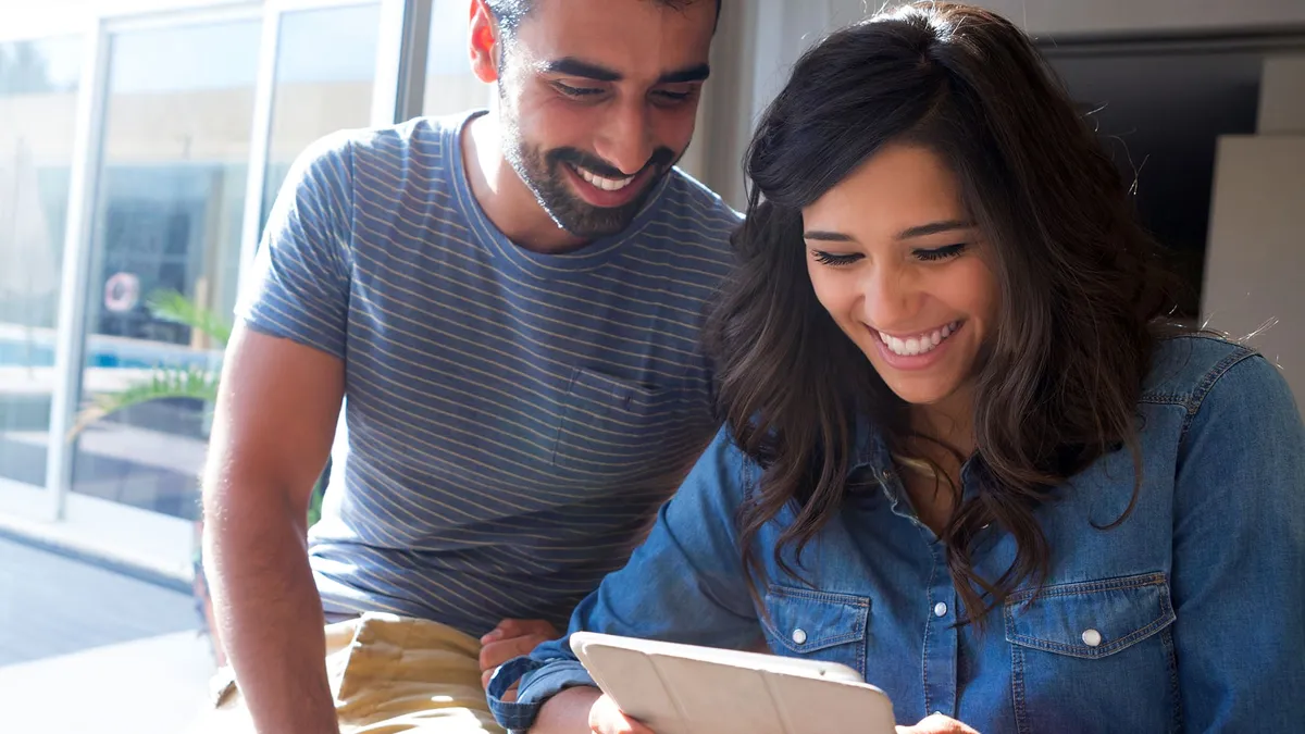 Couple happily using iPad by the window