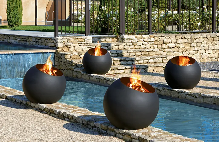 Four spherical fire pits on an outdoor patio.