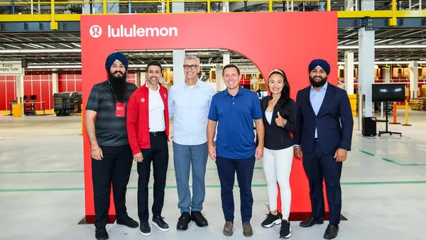 Six people pose inside a distribution center.