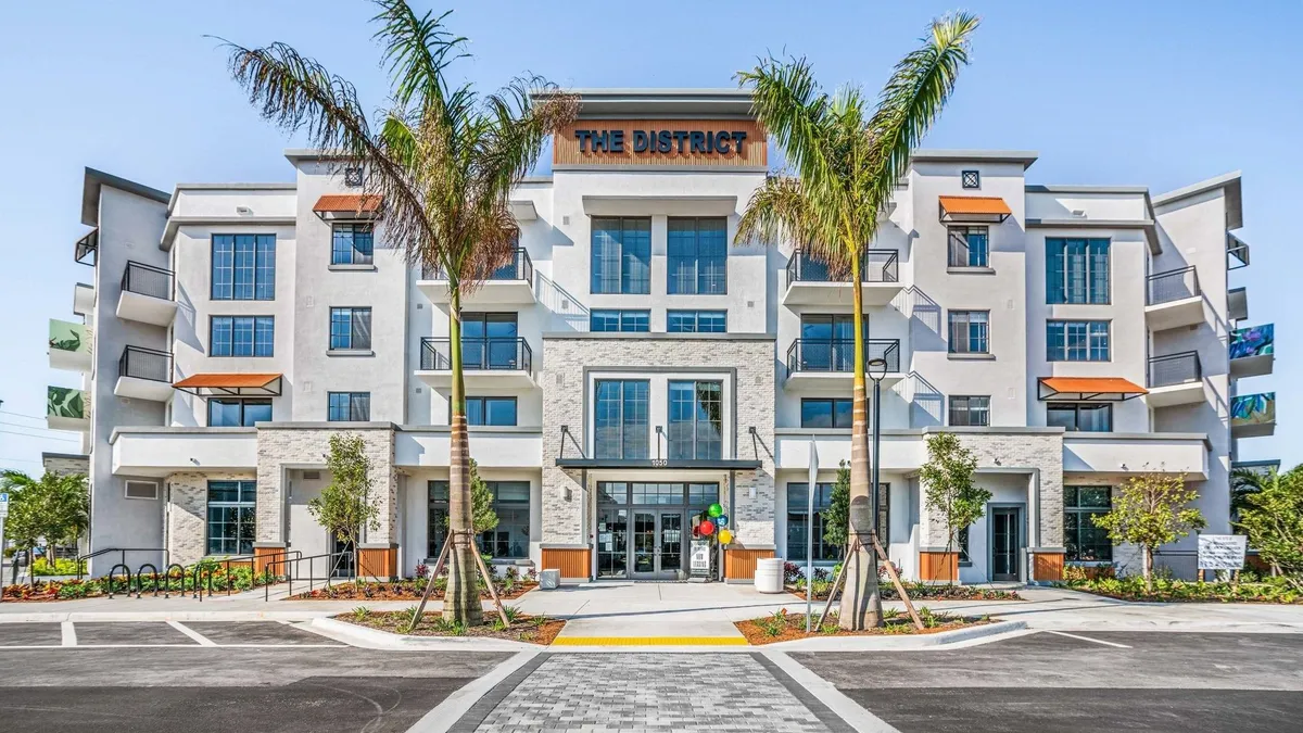 White apartment building with palm trees in the foreground.