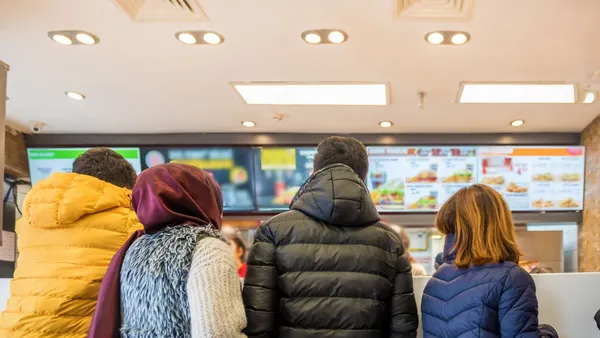 Four customers wait in line at a fast food restaurant.