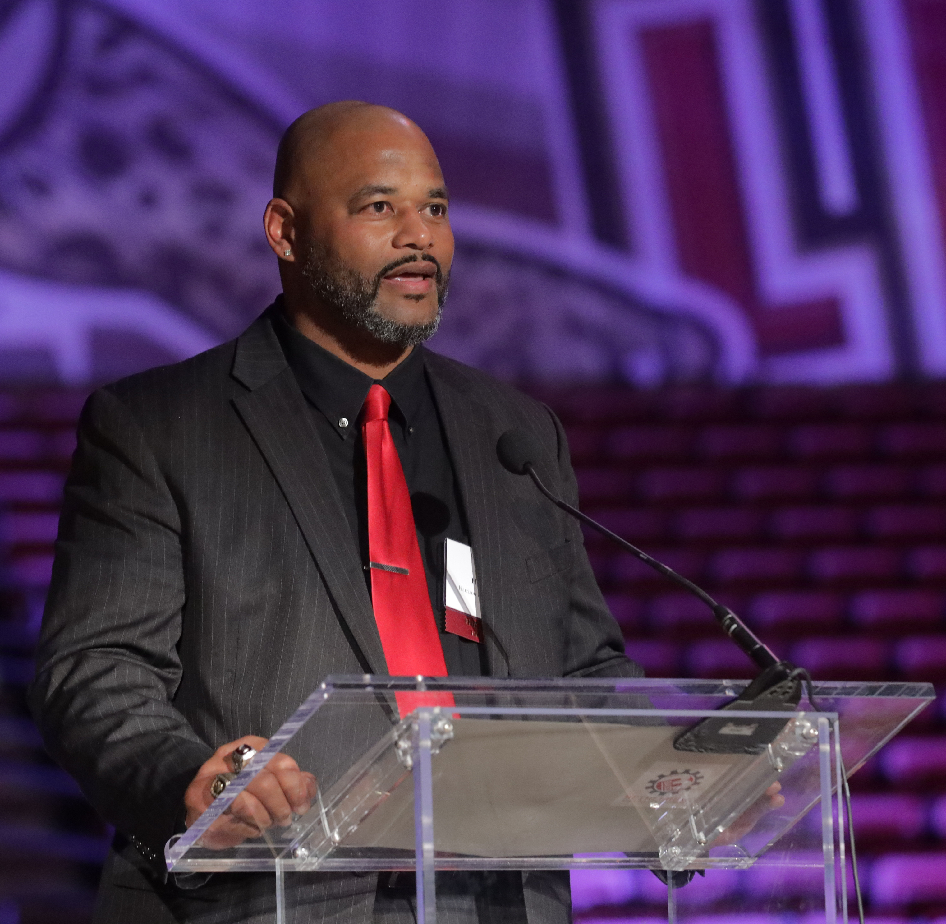 A Black high school principal speaks at a podium.