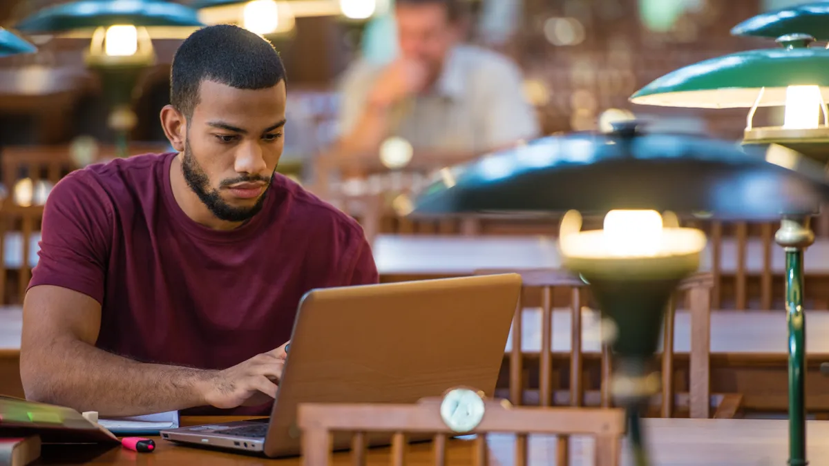 A Black student studies using a laptop in a campus library