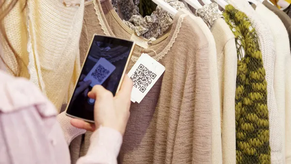 A person scans a QR code on a tag in a clothing store.