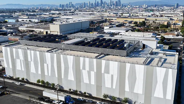 An aerial view of a large rectangular building with a city skyline in the background.