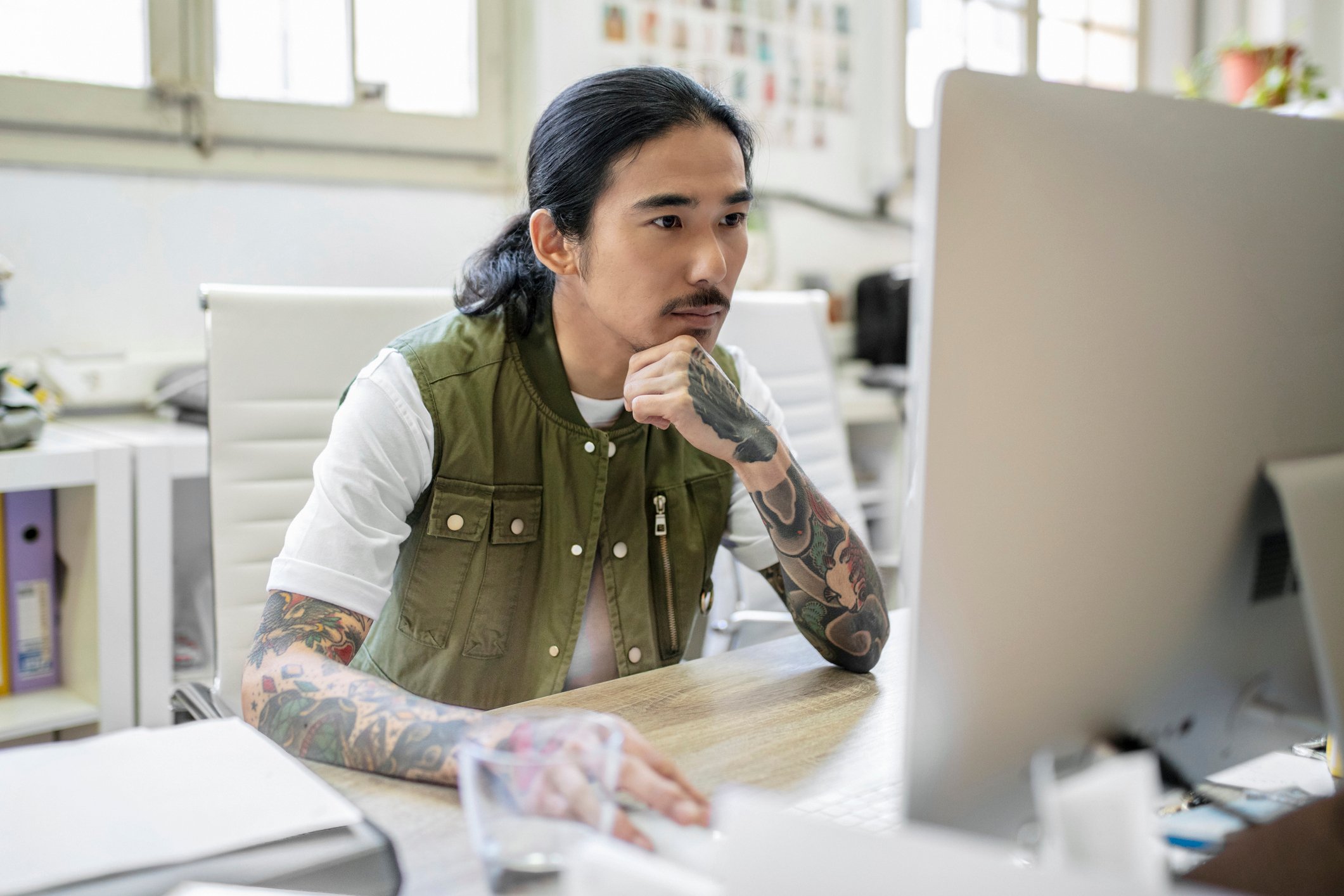 Businessman with tattoo using computer at desk - stock photo