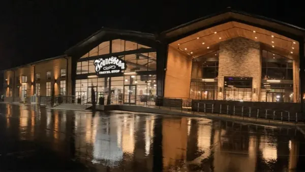 A photo of the exterior of a building at night. An illuminated sign on the front of the store says "Tennessean Travel Stop"