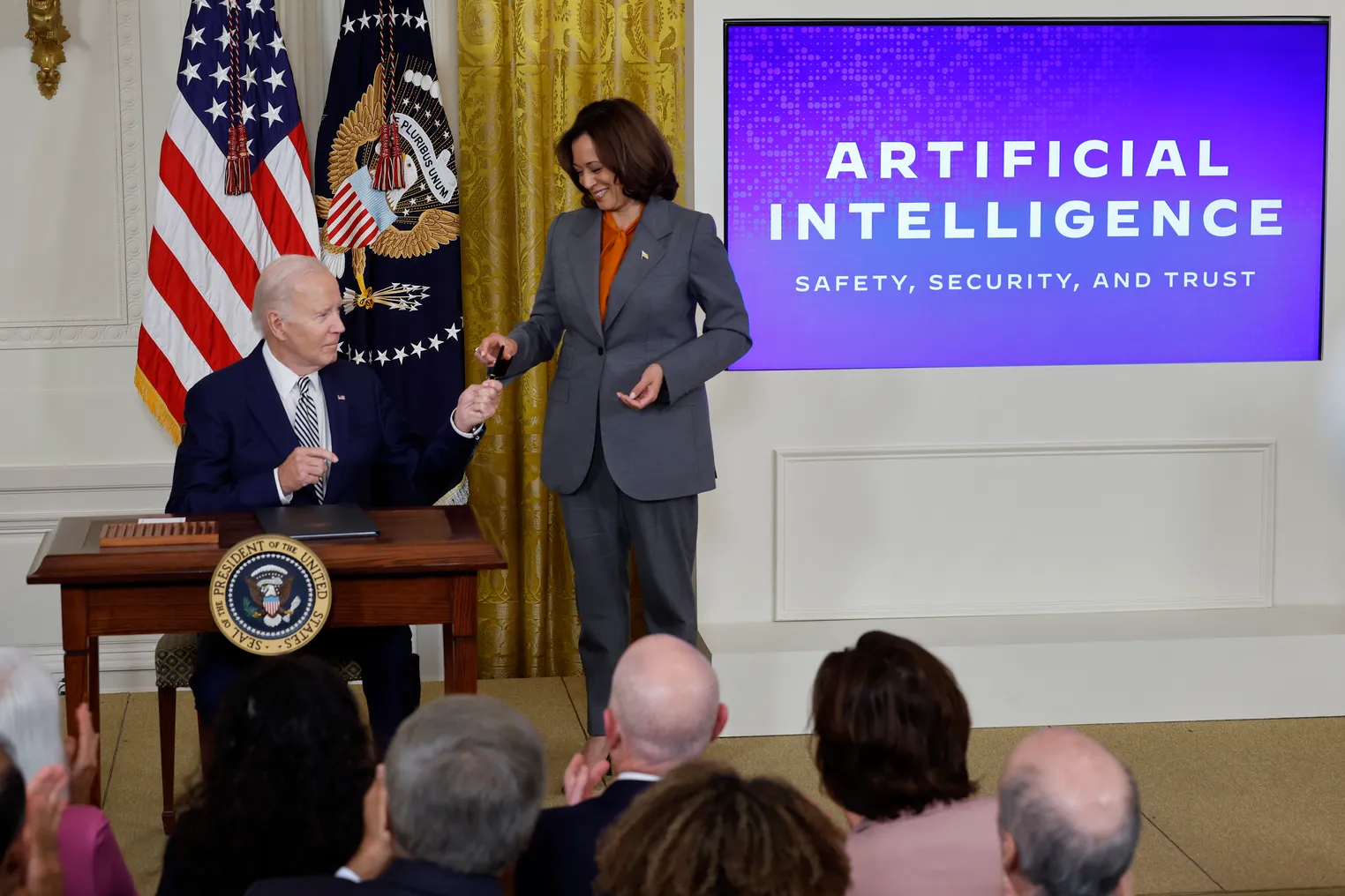 President Joe Biden hands Vice President Kamala Harris a pen used to sign an executive order at the White House.