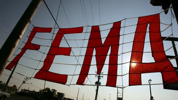 Large red letters that say "FEMA" in a large net between trees.