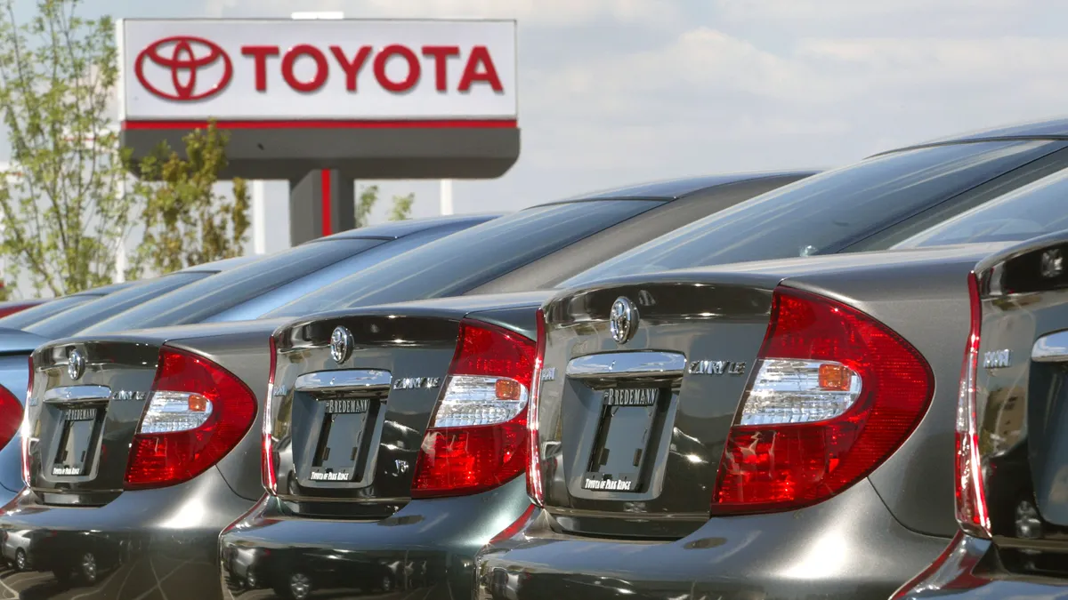 Several silver 2002 Toyota Camrys are lined up, with a Toyota sign in the back.