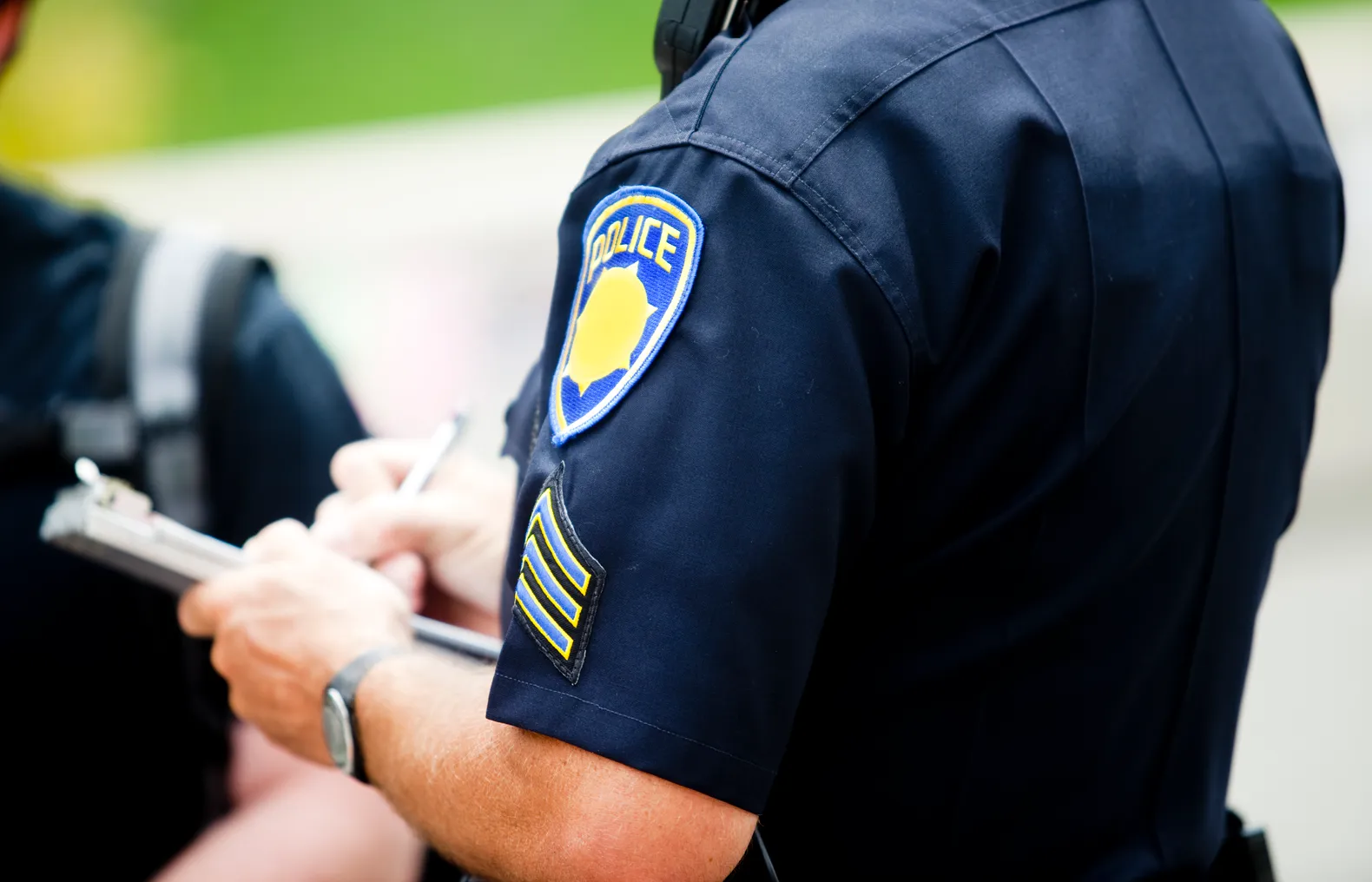 A police officer writes up a ticket to in front of a high school student.