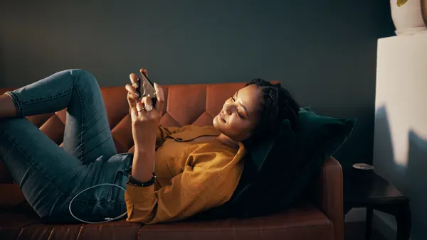 A person laying on a couch while scrolling on their phone