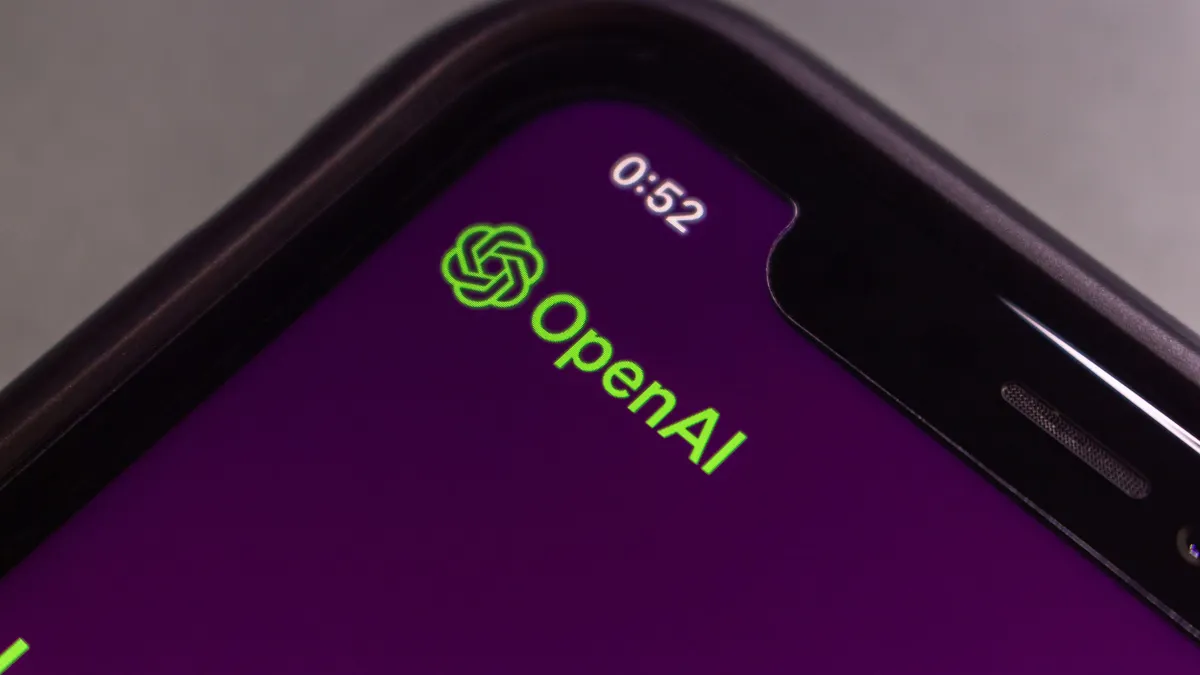 Extreme close-up of a smartphone screen showing a purple background with the OpenAI logo and the time “0:52” in the corner.