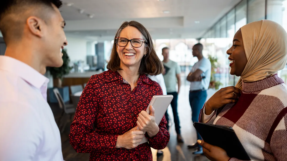 Professionals talking in office smiling.