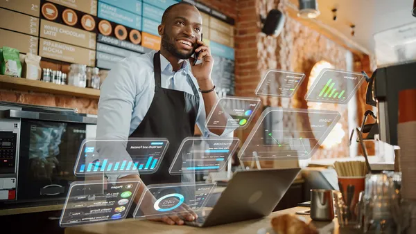 Coffee shop owner using computer and talking on phone