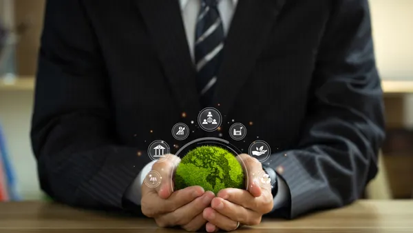 Businessman holding green world ball with Esg icons.Ethical and sustainable investing.