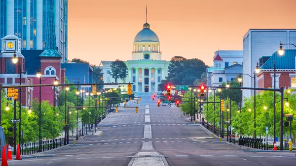 Montgomery, Alabama, with the state Capitol and city buildings at dawn. A series of traffic lights are all red.
