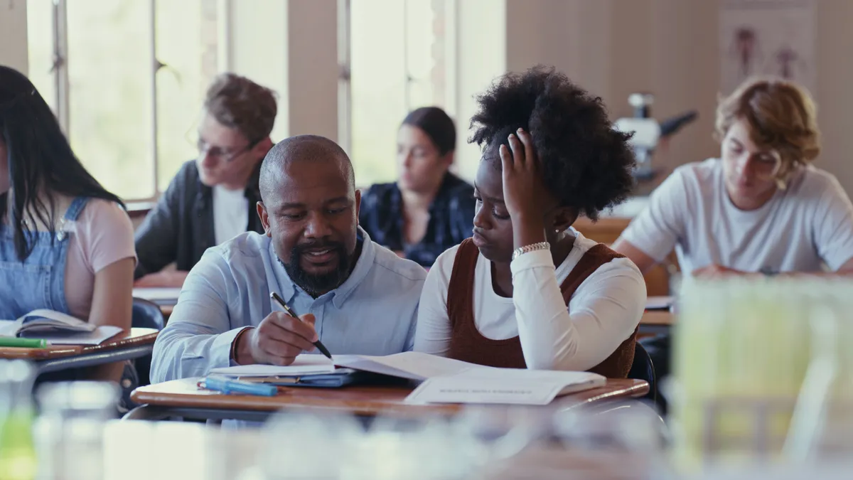 A teacher works one-on-one with a student on an assignment in the classroom.