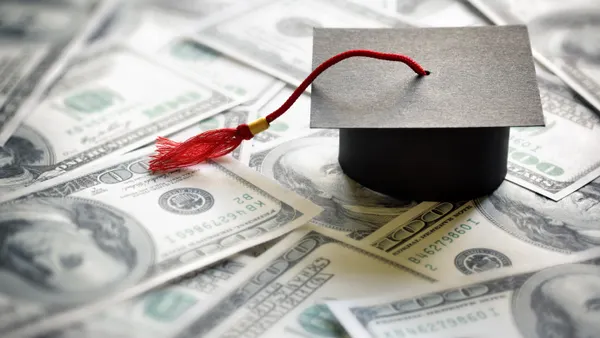 A graduation cap sits atop cash bills
