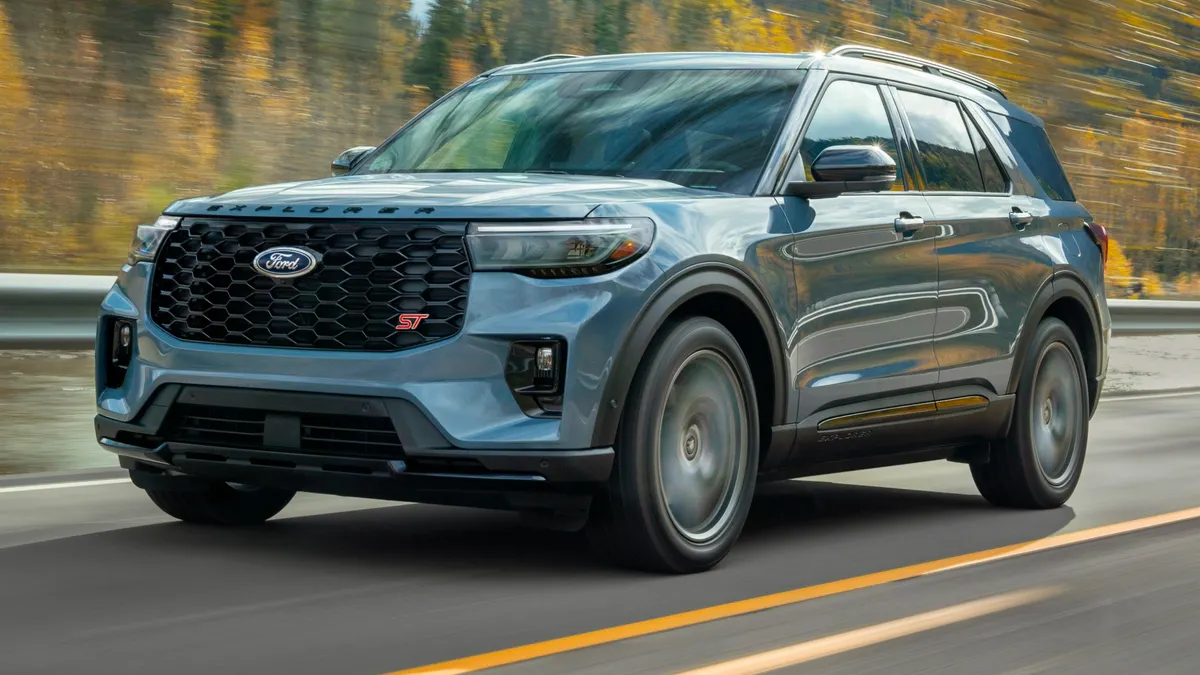 A 2025 Ford Explorer SUV driving on a road with trees in the background.