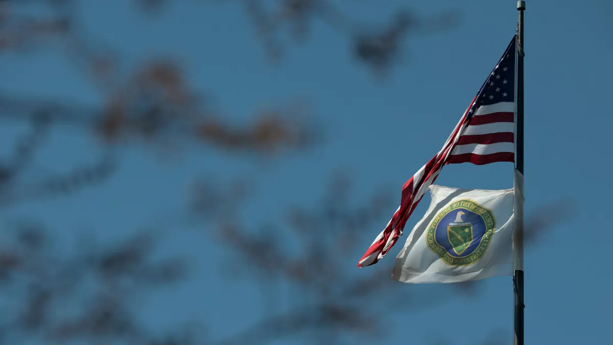 A U.S. flag and the flag of the U.S. Department of Energy fly outside its building.