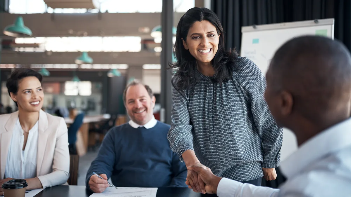 A businesswoman and businessman shaking hands during a meeting in a modern office