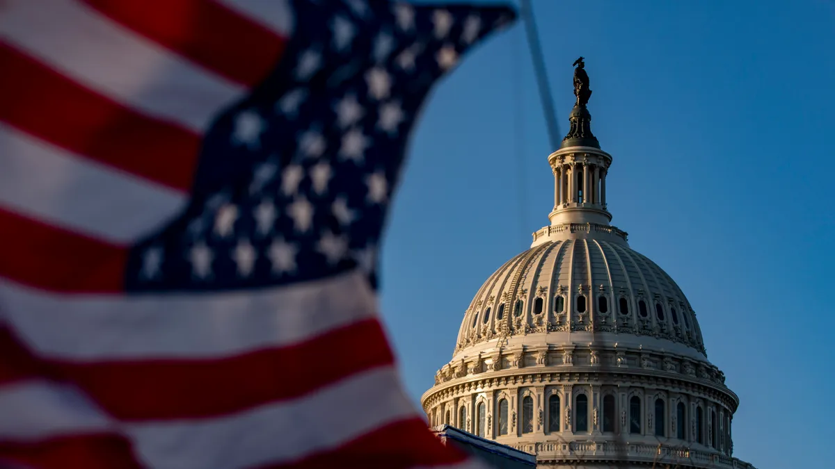 A picture of the US Capitol building with the American flag waving in front of it