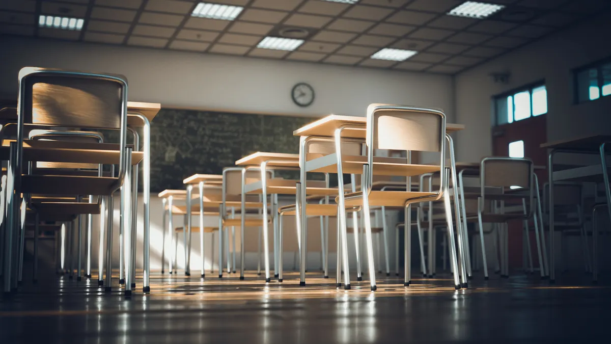 A classroom with empty desks is pictured from the floor angle.