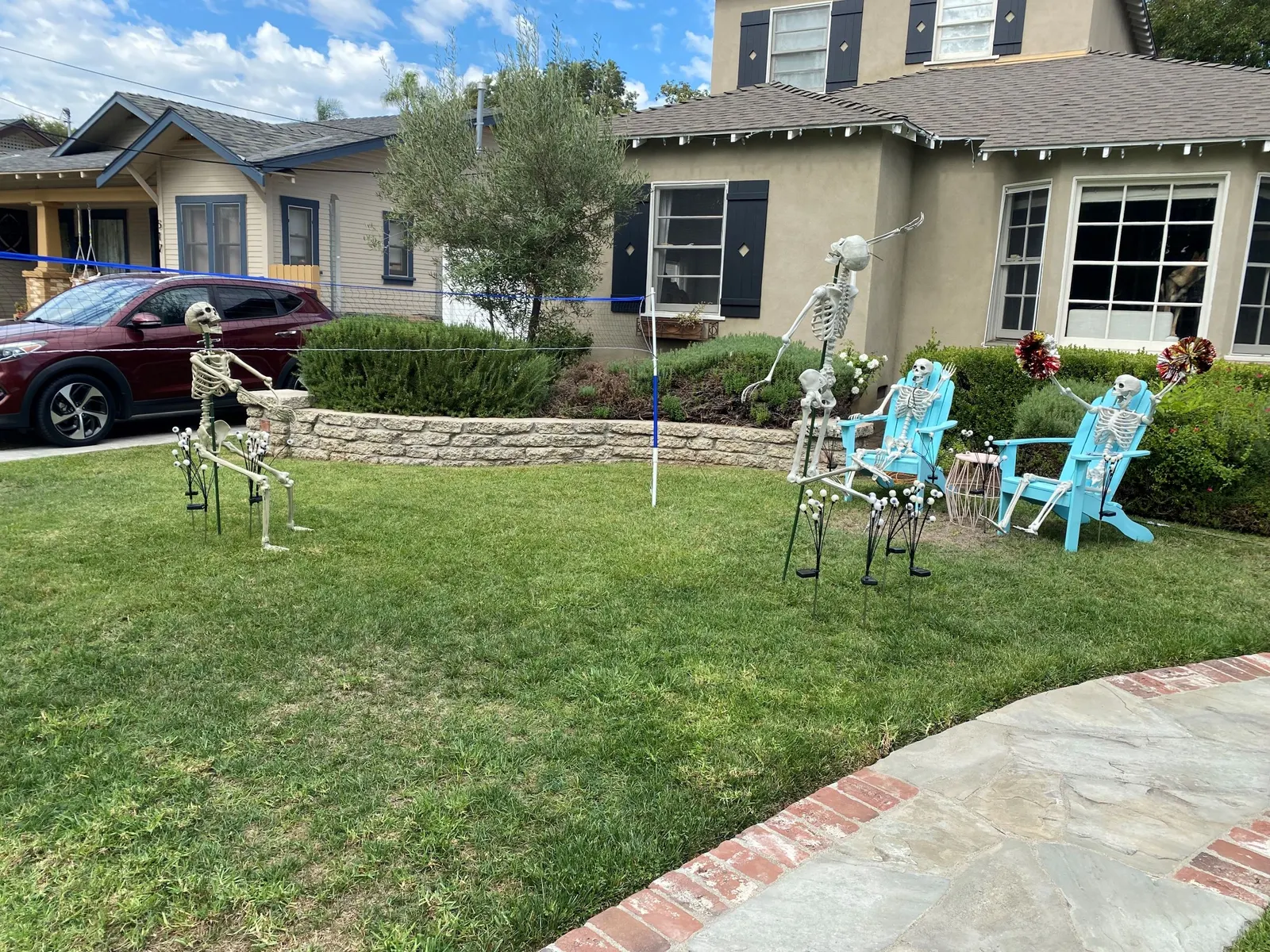 Skeletons playing volleyball in a yard.