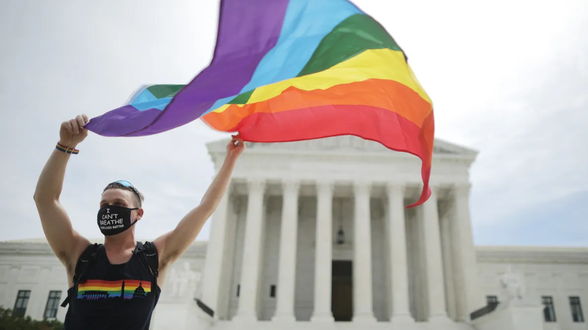 The LGBTQ+ pride flag flies in the hands of an activist.