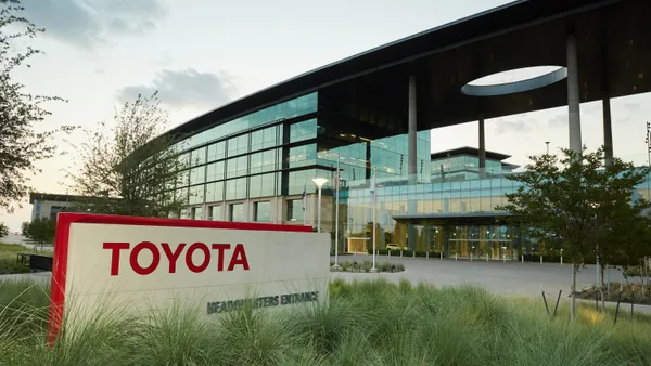 An exterior red and white Toyota sign at the entrance of company's North America Headquarters in Plano, Texas.