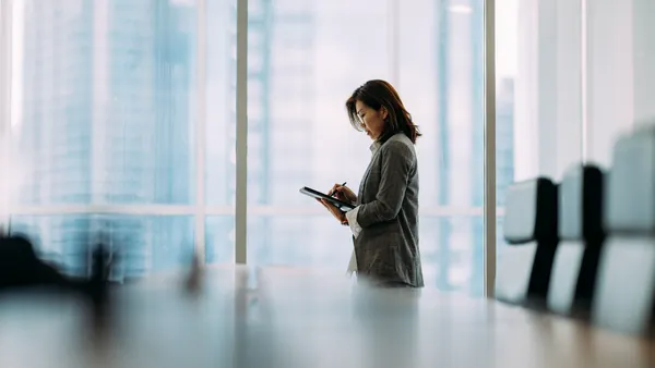 an executive reviews information on their tablet inside a boardroom