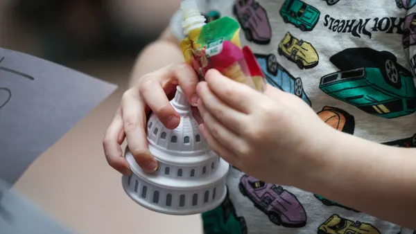 A close-up of a child holding a foam replica of the U.S. Capitol