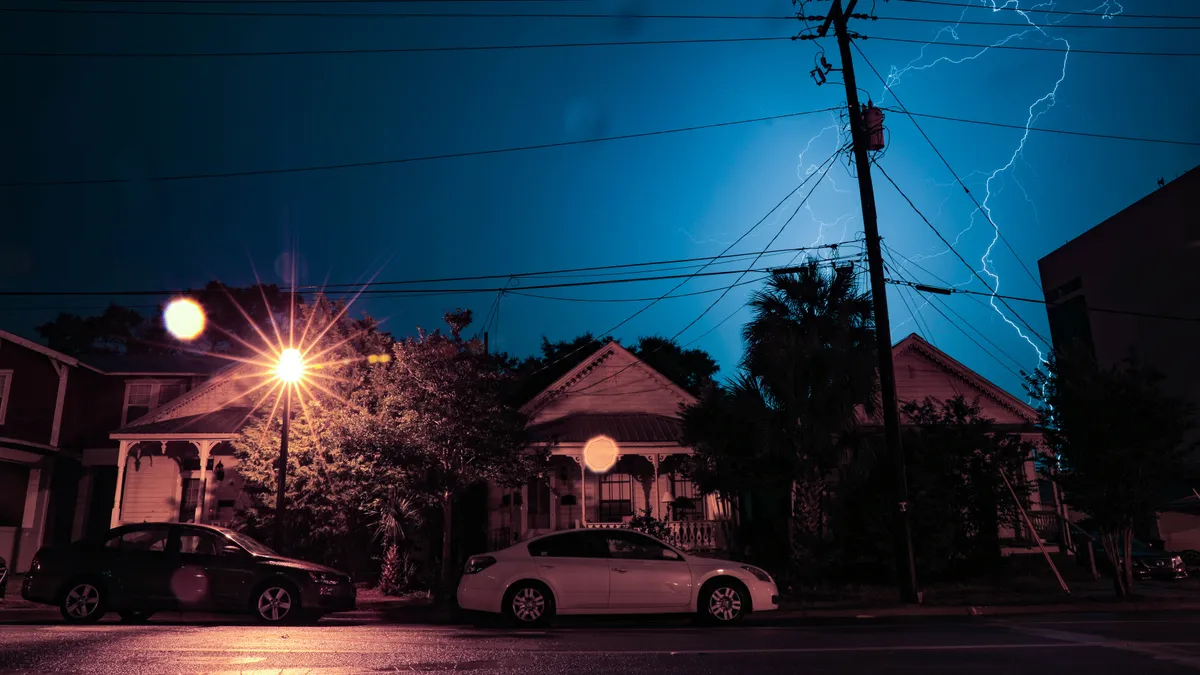 downtown lightning bolt shoots across the sky over houses and electric lines