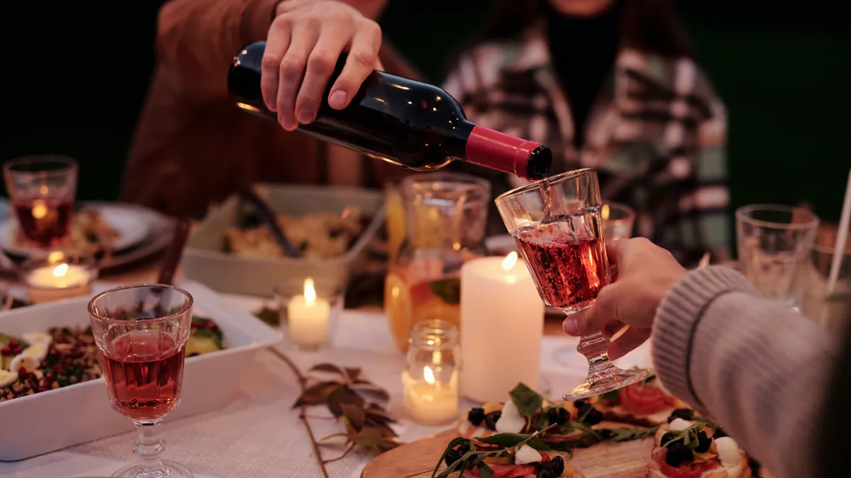 A hand pours wine at a lively dinner