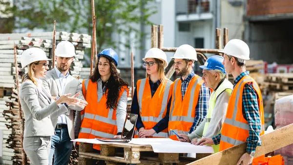 A group of construction workers stand around on a jobsite having a meeting.